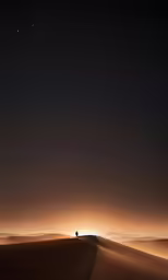 the person is walking on a sand dune at night