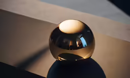 a shiny gold ball stands alone in a dim spot