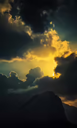 the setting sun shines through cloud covers on a mountain