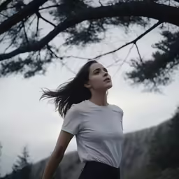 the woman is standing under the trees near the woods