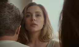 a young woman is looking in the mirror with an older man watching
