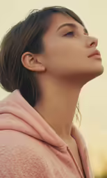 a beautiful woman in a pink robe stares up at the sky