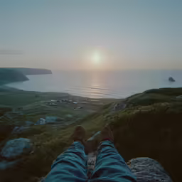 person with feet on camera looking at the ocean