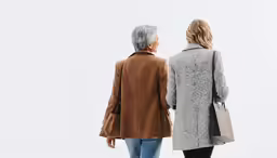two women in jackets standing in front of the camera