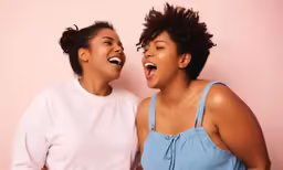 two women laugh while they hold their heads together