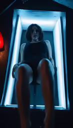 a person sits on a stool in the dark