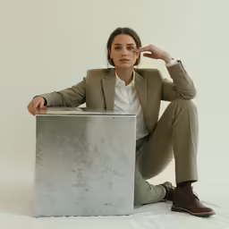 a woman sitting on a stool with her foot on her head