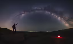 a person standing next to a red truck under a very pretty milky