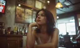 a young woman at a restaurant with her hand on her chin