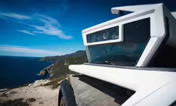 a photo taken through the rear view mirror of a vehicle driving on a road near a large body of water