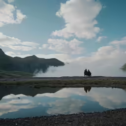 two people ride horses down a rocky landscape