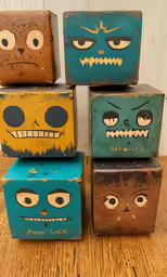 four painted boxes with faces are on the table
