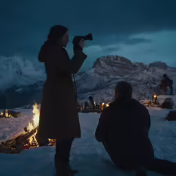 a man and woman taking pictures in the mountains at night