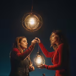 two beautiful women touching hands together holding a lantern