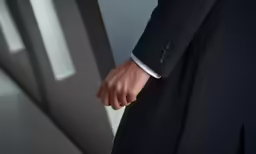 closeup on hand in black suit with white collar