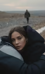 a girl wearing black jacket with a man in the distance