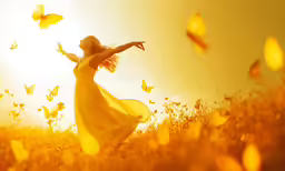a girl wearing a yellow dress on top of a field with butterflies flying in the sky