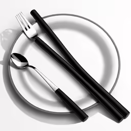 a white plate with black and silver utensils and fork on it