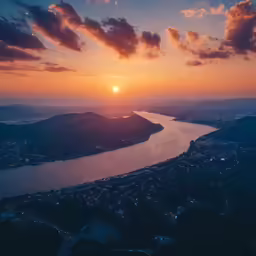 a sun sets over water and mountains
