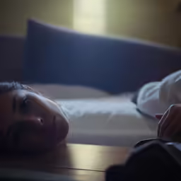 woman resting on bed with her hands crossed on the table