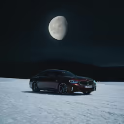 the bmw car is sitting in the snow near the moon