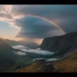 a rainbow arches over clouds in a valley