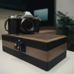an analog camera sits on top of a wooden box