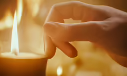 a candle that is lit with its hands on top