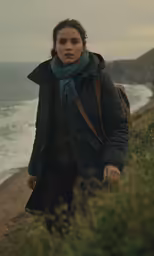 a woman looking concerned in the distance by the beach