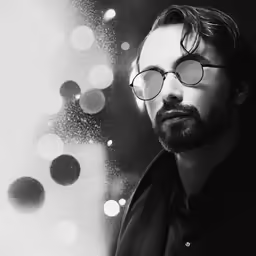 man with eye glasses leaning against an old photograph