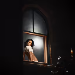 a woman standing at an open window with a plant in front of her