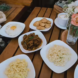 plates of food sitting on a table with flowers in the vase