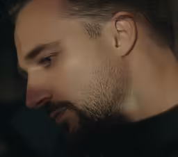 a man with beard and black shirt looking down