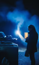 woman in black coat standing in front of vehicle