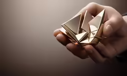 someone holding up gold paper foldings