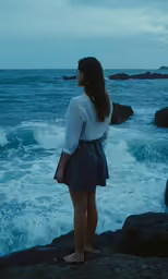 woman standing on rocks looking out into the water