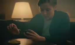 a woman sitting at a table checking her phone