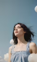 a woman standing in the clouds with her hair blowing