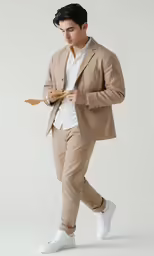 a man in beige suit with one foot on his hip