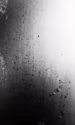 rain is falling down over a window with a stop light