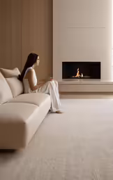 a woman is sitting on the couch in front of the fire place