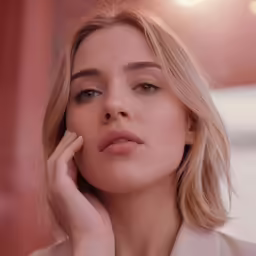 a beautiful blonde haired woman holding her hands up against her ear