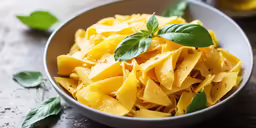 the yellow pasta in the bowl has basil and water