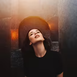 a young woman is looking up at the sun coming out