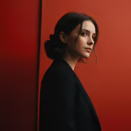 a woman looking down standing in a red room