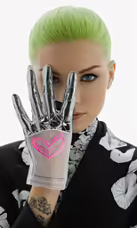 a woman is wearing a black suit with green hair and has her hands in a heart shaped box