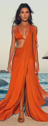 a woman in an orange dress on the beach