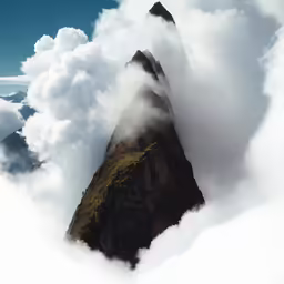 mountains with clouds blowing in the foreground and a large rock