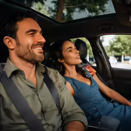 two people in a car, one is sitting in the passenger seat