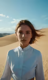 a beautiful young woman standing in the desert wearing a white shirt
